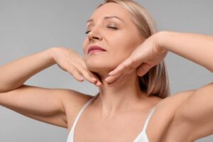 Woman touching her neck, highlighting smooth skin and rejuvenated jawline after a neck lift procedure.