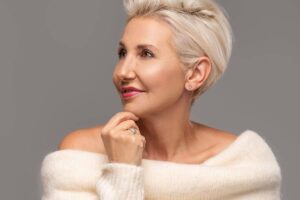 Elegant mature woman with short blonde hair and smooth skin, showcasing youthful facelift results