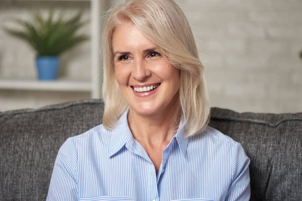 Mature woman smiling with radiant complexion, reflecting final facelift results after months of healing and recovery