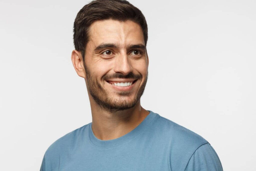 Smiling man in blue shirt, representing fast recovery benefits of closed rhinoplasty with minimal swelling and no scarring.