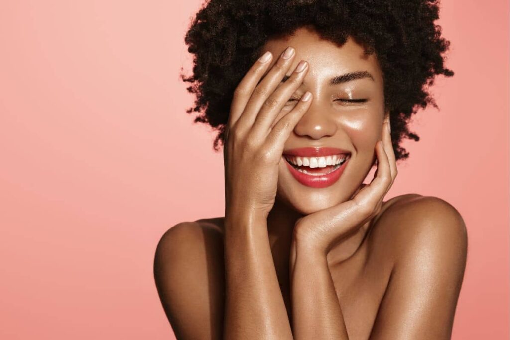 Joyful woman smiling with hand on face, symbolizing confidence after selecting the ideal rhinoplasty technique