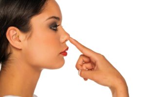 Woman touching her rounded nasal tip, illustrating a common reason for undergoing rhinoplasty to refine nose shape.