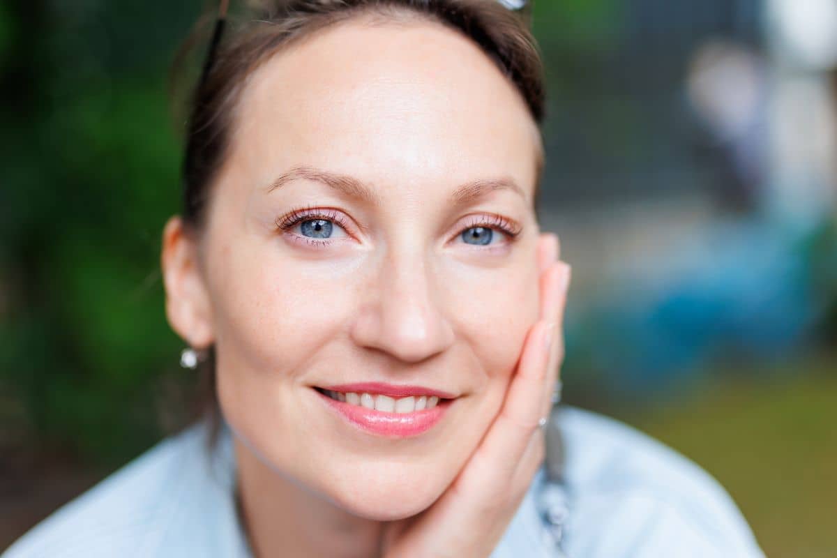 Woman with symmetrical features and relaxed smile, representing successful rhinoplasty for a previously crooked nose